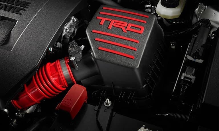 A close-up of a car engine's red and black air intake system with a dominant 