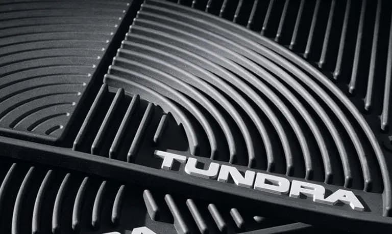 Close-up of a black molded car floor liner with the word 